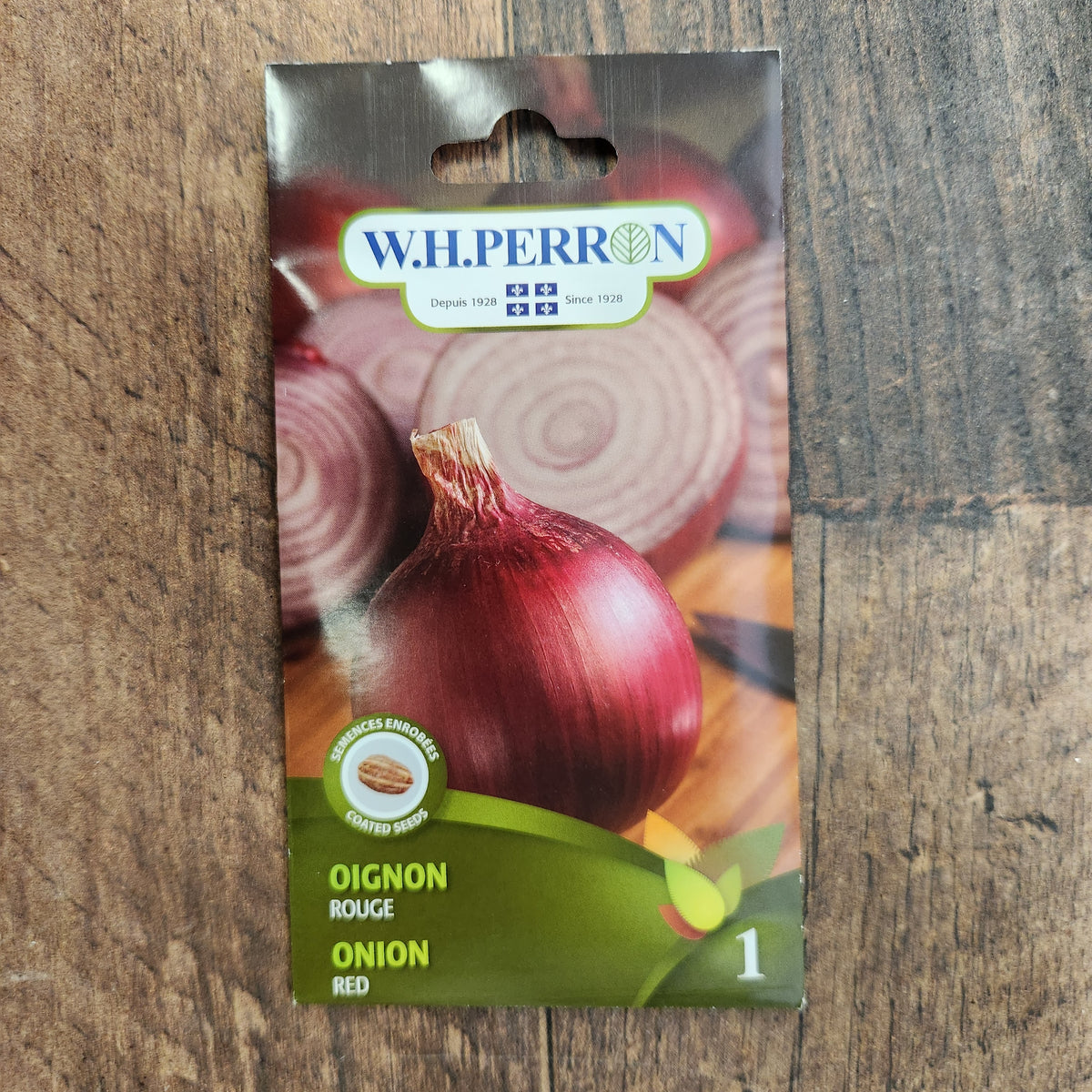 Sachet de semences W. H. Perron : Oignon rouge (Allium cepa). L'emballage présente le nom de la sélection et une illustration de la plante ou de la récolte. Cette photographie montre la face avant du sachet, avec les renseignements imprimés visibles et les éléments graphiques qui permettent de reconnaître le produit parmi les autres semences de la gamme.