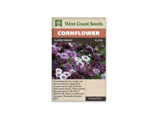 Sachet Classic Magic de West Coast Seeds sur fond blanc. La photo montre un groupe de fleurs pourpre foncé, mauves et presque blanches. Plusieurs ont des pointes claires ou un centre violet, sur des tiges vertes visibles entre les fleurs. Le bandeau orangé indique Cornflower; Classic Magic et FL2184 se lisent dans la bande brune.