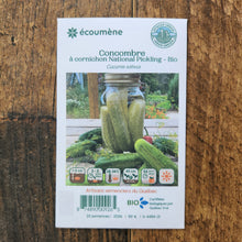 Sachet de semences Concombre à cornichon National Pickling. Emballage blanc photographié de face sur un fond de bois brun. Une image du végétal occupe la partie centrale, sous le nom imprimé. De petits pictogrammes et un code-barres apparaissent au bas du sachet. La marque Écoumène figure dans la partie supérieure de cette présentation.
