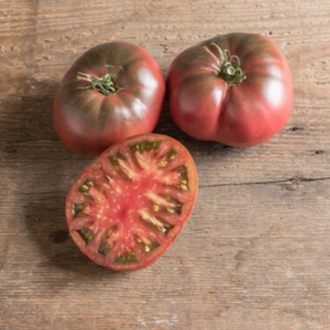 Plant indéterminé de tomate Black Krim biologique solidement tuteuré, portant de gros fruits rouge foncé à brun pourpre, parfois presque noirs, parmi un feuillage vert sain. La présentation montre les nuances variables des épaules et l’accès nécessaire pour soutenir les grappes et évaluer doucement la maturité. Pour la présentation visuelle, observez chaque plant avant d’ajuster les soins.