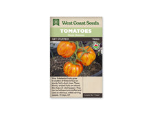 Sachet West Coast Seeds portant les mentions Tomatoes, Main Season et Get Stuffed! La photo montre des tomates lobées jaune orangé, rayées de rouge, attachées à des tiges vertes au-dessus d’un sol sombre. Un logo biologique rond apparaît à droite. Le nom et le code TM846 figurent sous les bandeaux verts de la marque.