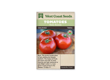 Sachet West Coast Seeds portant les mentions Tomatoes, Main Season et Galahad. Trois grosses tomates rouges, avec des pédoncules verts, sont posées sur une surface de bois brun. Un logo biologique rond apparaît à droite de la photo. Le nom de la variété et le code TM856 figurent sous les bandeaux verts de la marque.