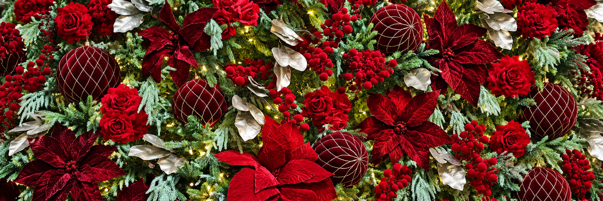 Poinsettias rouges, boules en velours bourgogne et feuillage givré dans un sapin décoré chez Floréal.