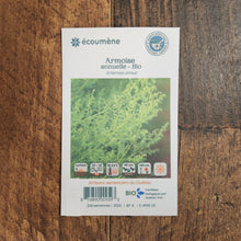 Sachet de semences Armoise annuelle. Emballage blanc photographié de face sur un fond de bois brun. Une image du végétal occupe la partie centrale, sous le nom imprimé. De petits pictogrammes et un code-barres apparaissent au bas du sachet. La marque Écoumène figure dans la partie supérieure de cette présentation.