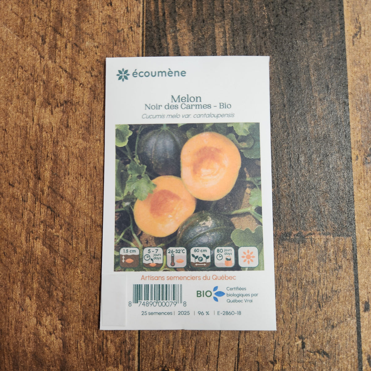 Sachet de semences Melon Noir des Carmes. Emballage blanc photographié de face sur un fond de bois brun. Une image du végétal occupe la partie centrale, sous le nom imprimé. De petits pictogrammes et un code-barres apparaissent au bas du sachet. La marque Écoumène figure dans la partie supérieure de cette présentation.