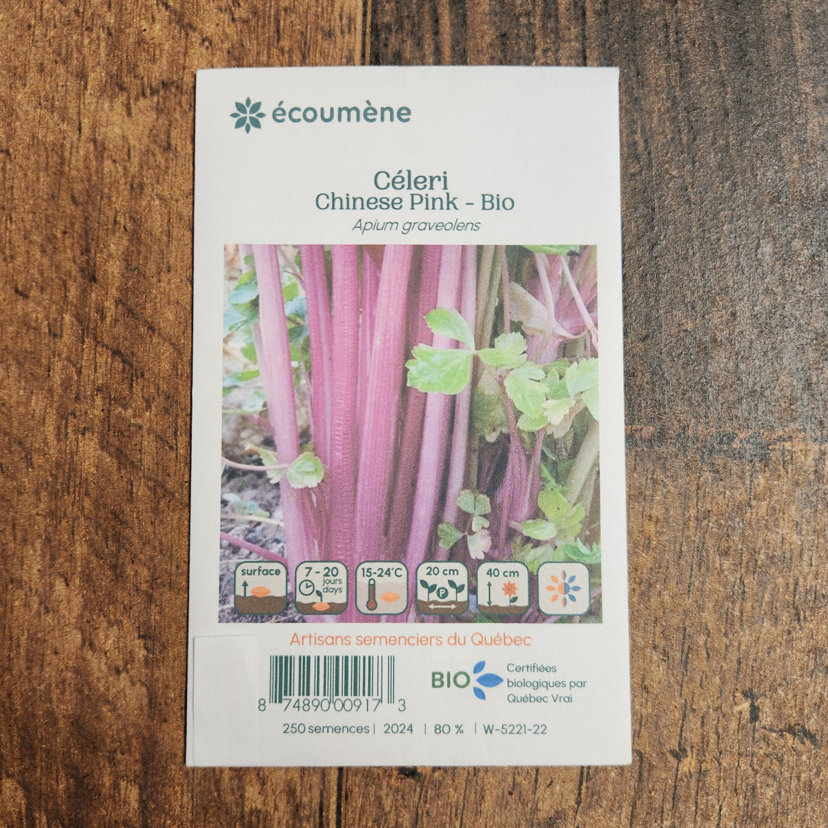 Sachet de semences Céleri Chinese Pink. Emballage blanc photographié de face sur un fond de bois brun. Une image du végétal occupe la partie centrale, sous le nom imprimé. De petits pictogrammes et un code-barres apparaissent au bas du sachet. La marque Écoumène figure dans la partie supérieure de cette présentation.